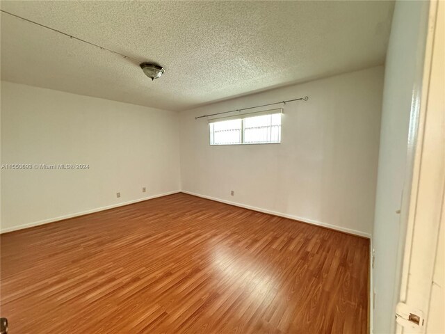 spare room with a textured ceiling and wood-type flooring