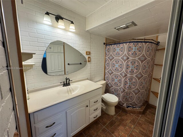 bathroom featuring brick wall, vanity, and toilet