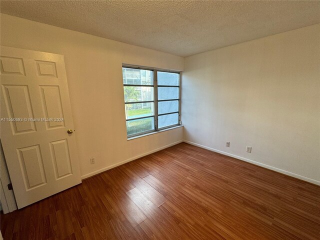 unfurnished room with a textured ceiling and dark wood-type flooring