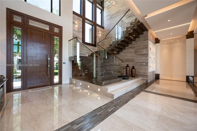 tiled entrance foyer featuring a healthy amount of sunlight, tile walls, and a high ceiling