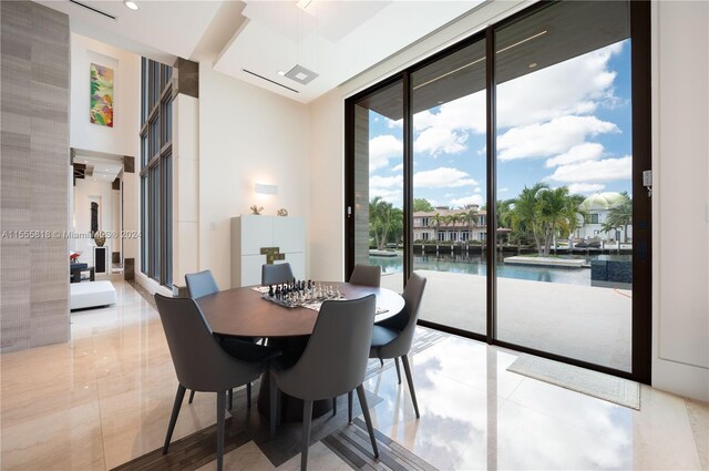 tiled dining area with a water view and floor to ceiling windows