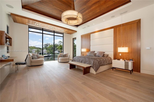 bedroom with wood ceiling, a tray ceiling, hardwood / wood-style floors, and a wall of windows