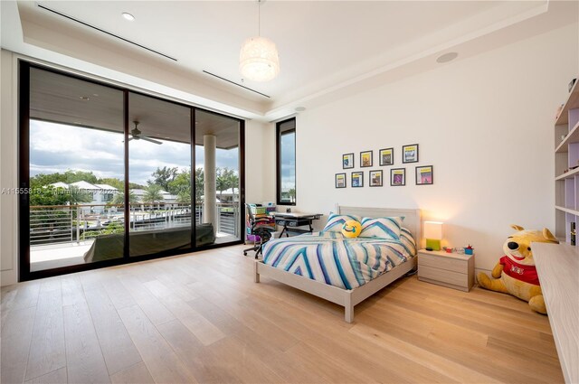 bedroom featuring expansive windows, multiple windows, light wood-type flooring, and access to outside