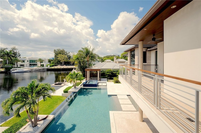 view of swimming pool with a patio, a water view, and ceiling fan