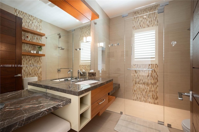 bathroom featuring vanity, a shower with door, toilet, and a healthy amount of sunlight