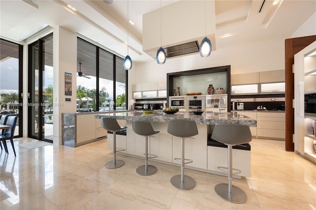 kitchen with dark stone counters, a healthy amount of sunlight, a kitchen breakfast bar, and light tile patterned floors