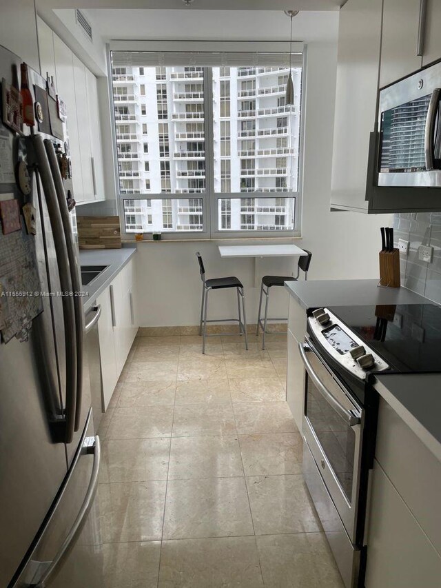 801 Brickell Key Blvd Unit 1610, Miami, FL 33131 - kitchen with stainless steel appliances, white cabinets, decorative light fixtures, and tasteful backsplash