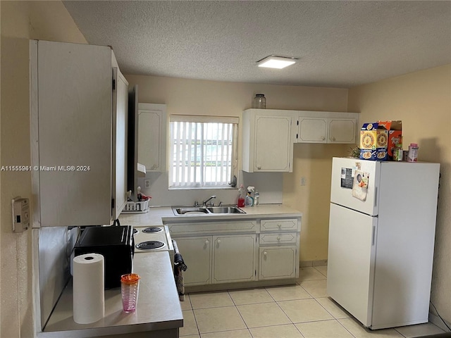 kitchen with white cabinets, white refrigerator, sink, a textured ceiling, and light tile patterned flooring