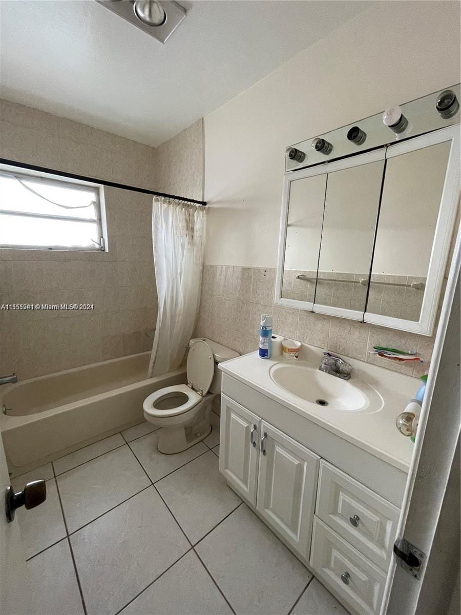 full bathroom featuring vanity, tile patterned floors, toilet, tile walls, and shower / tub combo