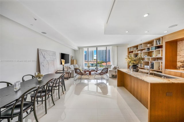 kitchen with sink, light stone countertops, floor to ceiling windows, a kitchen island, and light tile patterned floors