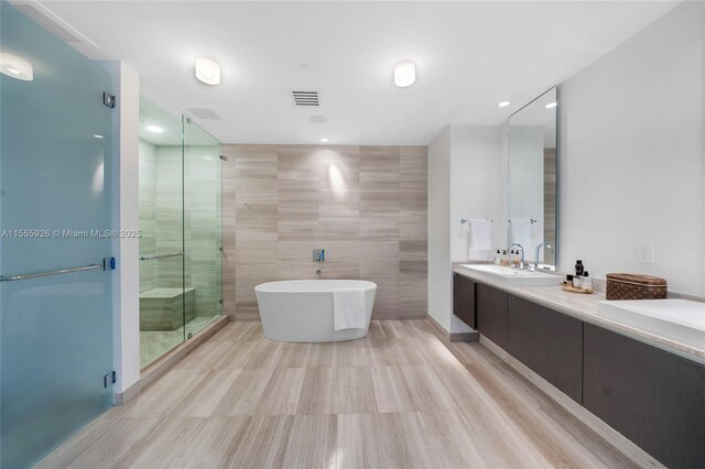 bathroom featuring tile walls, tile patterned flooring, double sink vanity, and a bath