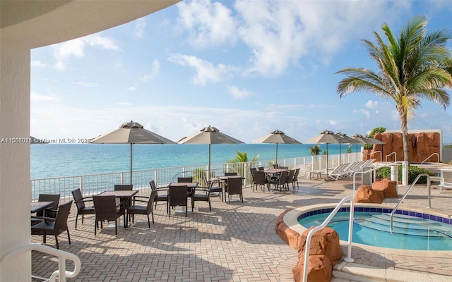 view of swimming pool with a water view, a patio area, and a hot tub