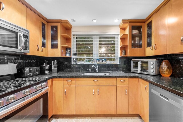 kitchen with dark stone countertops, tasteful backsplash, sink, appliances with stainless steel finishes, and light tile patterned flooring