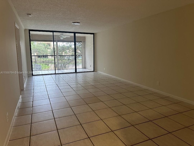 tiled empty room with a textured ceiling, expansive windows, and ceiling fan