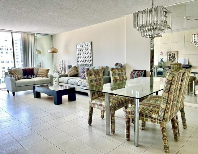 dining space with floor to ceiling windows, light tile floors, a textured ceiling, and a chandelier