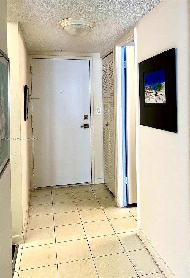 corridor featuring light tile floors and a textured ceiling