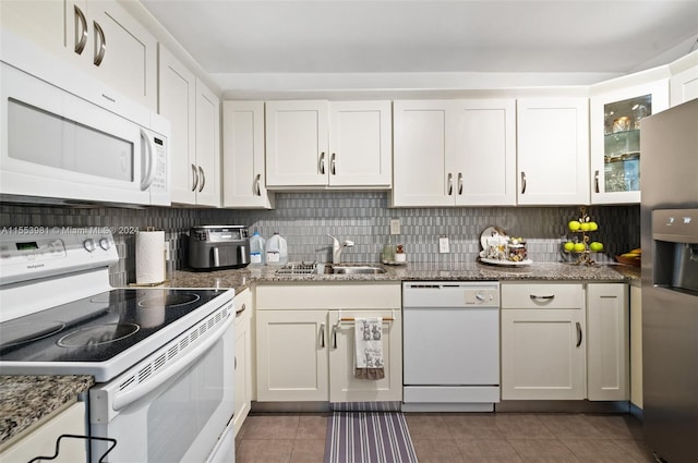 kitchen featuring tasteful backsplash, white appliances, dark tile flooring, sink, and white cabinets