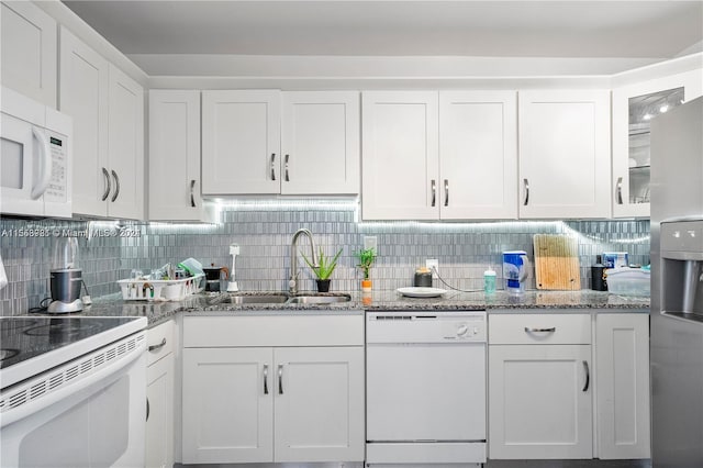 kitchen featuring light stone counters, white cabinets, backsplash, white appliances, and sink