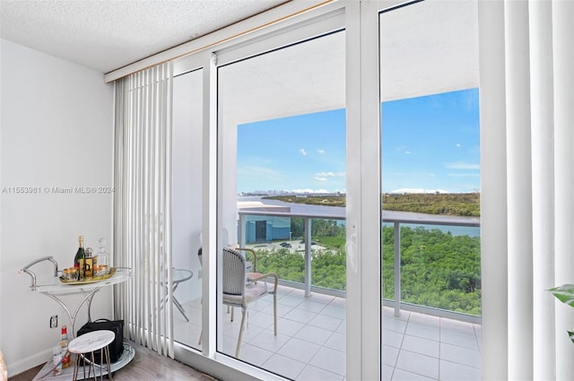 doorway to outside featuring light tile floors and a textured ceiling