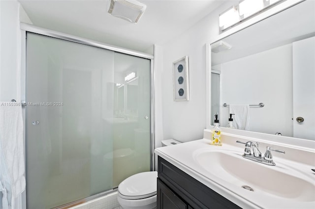 bathroom featuring a shower with shower door, large vanity, and toilet