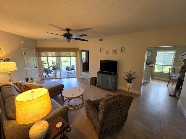 tiled living room with ceiling fan and a textured ceiling