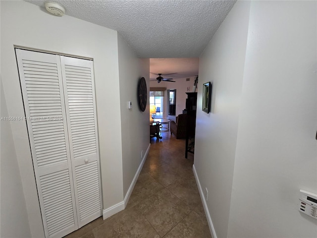 corridor featuring a textured ceiling and dark tile patterned floors