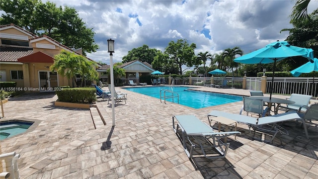 view of pool with a hot tub and a patio