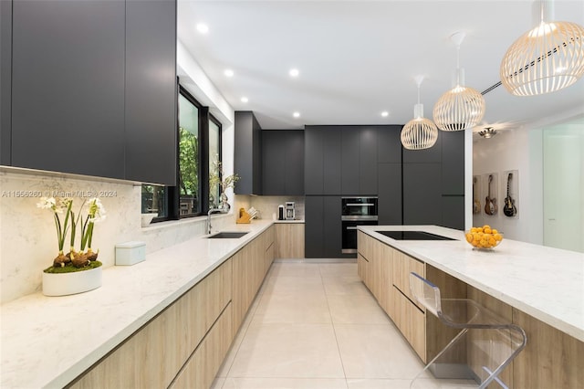 kitchen featuring light stone counters, sink, decorative backsplash, and hanging light fixtures