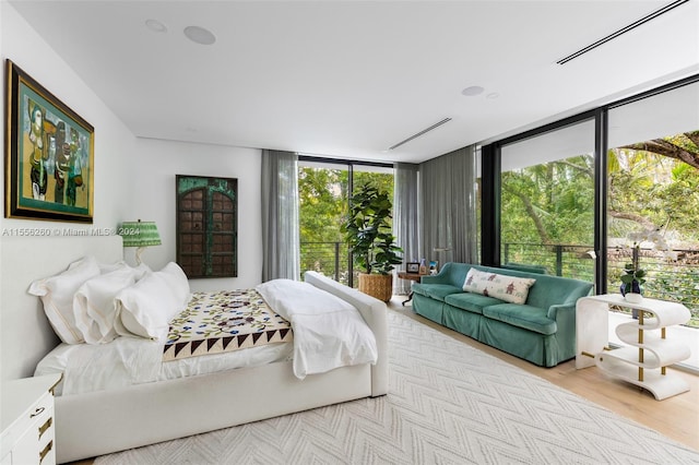 bedroom featuring light wood-type flooring and a wall of windows