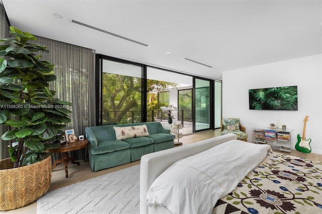 bedroom with floor to ceiling windows and light hardwood / wood-style floors