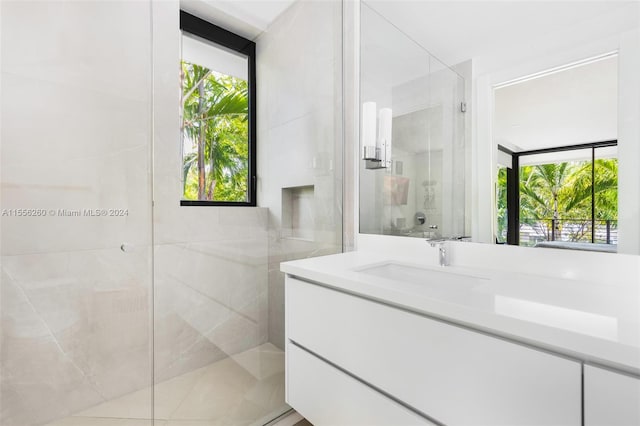 bathroom with a healthy amount of sunlight, a shower with door, and vanity