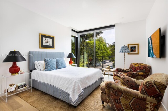 bedroom with floor to ceiling windows and light hardwood / wood-style floors