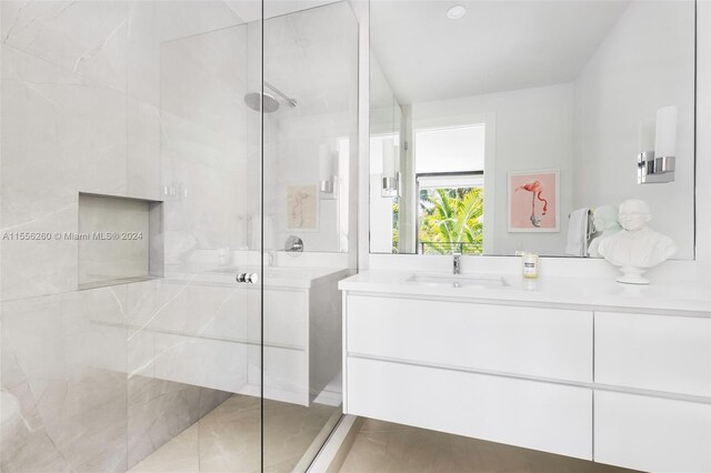 bathroom with tiled shower, vanity, and tile patterned floors