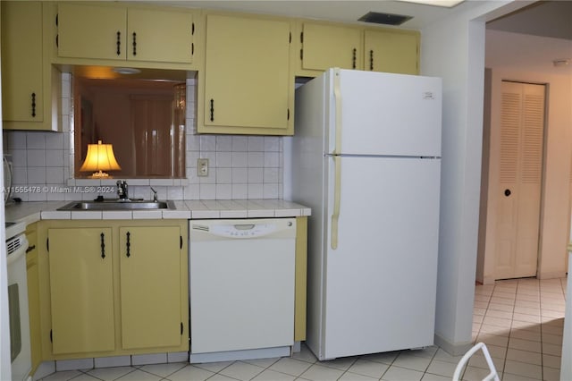 kitchen featuring backsplash, white appliances, sink, light tile patterned floors, and tile countertops