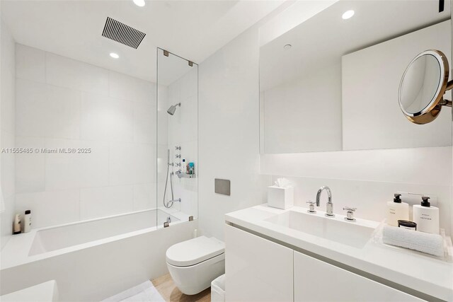 full bathroom featuring vanity, tiled shower / bath combo, and toilet