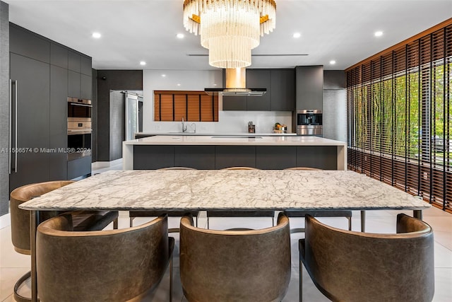 kitchen featuring sink, a spacious island, hanging light fixtures, wall chimney exhaust hood, and a chandelier