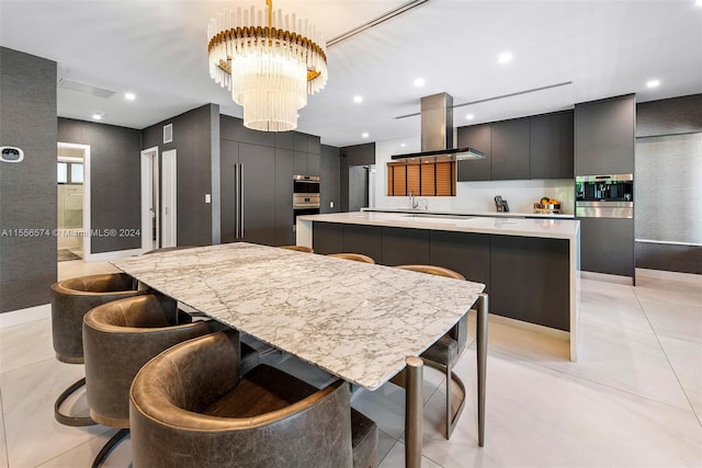 kitchen with island range hood, stainless steel oven, a center island, light tile patterned flooring, and an inviting chandelier