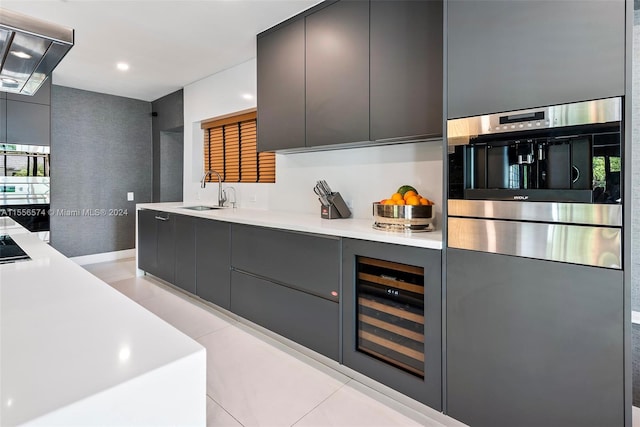 kitchen with wine cooler, sink, stainless steel oven, and exhaust hood