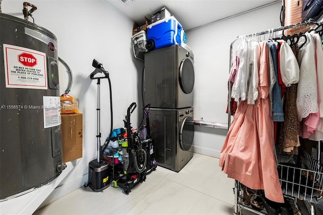 washroom with stacked washer / drying machine and water heater