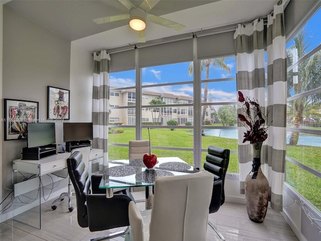 home office with light wood-type flooring, ceiling fan, a healthy amount of sunlight, and a water view