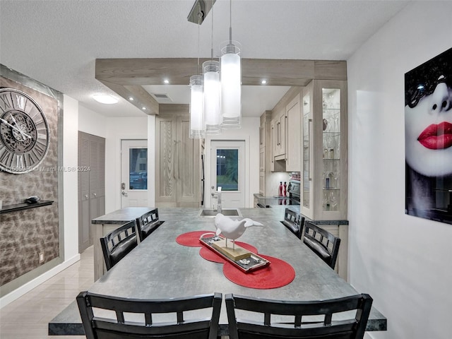 dining room featuring a textured ceiling, sink, and light wood-type flooring