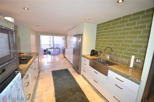 kitchen with sink, light tile floors, stainless steel appliances, tasteful backsplash, and white cabinetry