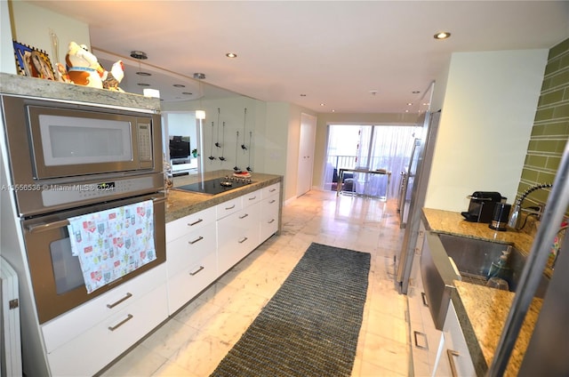 kitchen with stainless steel appliances, light tile flooring, dark stone counters, white cabinets, and hanging light fixtures