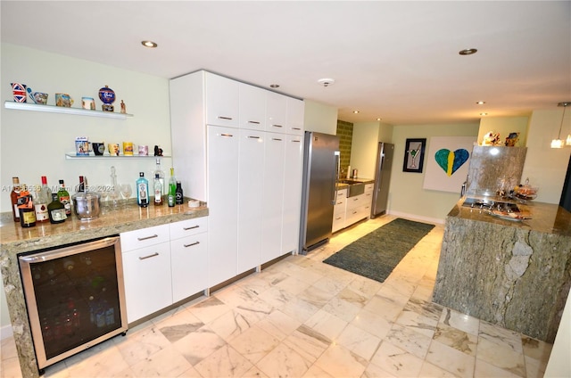 kitchen with white cabinets, wine cooler, stainless steel refrigerator, and light stone counters