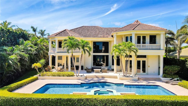 rear view of property featuring a balcony, a pool with hot tub, and a patio