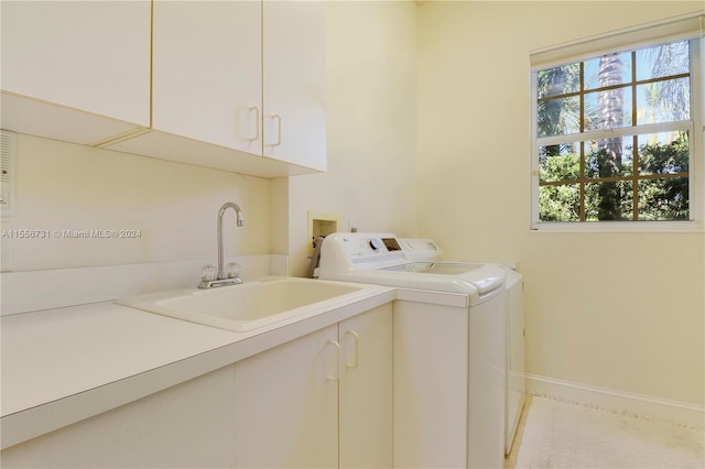 laundry area with hookup for a washing machine, cabinets, washing machine and clothes dryer, and sink