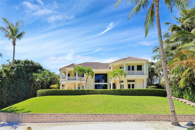 mediterranean / spanish home featuring a balcony and a front lawn