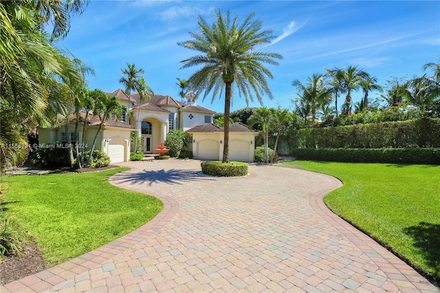 mediterranean / spanish home featuring a front yard and a garage