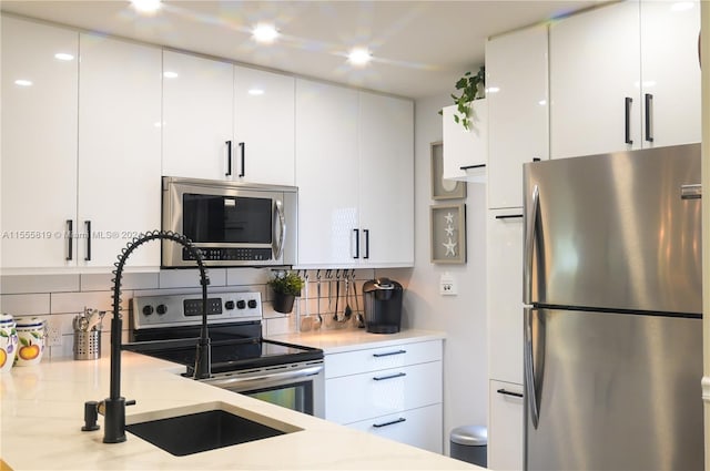 kitchen with white cabinets, sink, stainless steel appliances, and tasteful backsplash