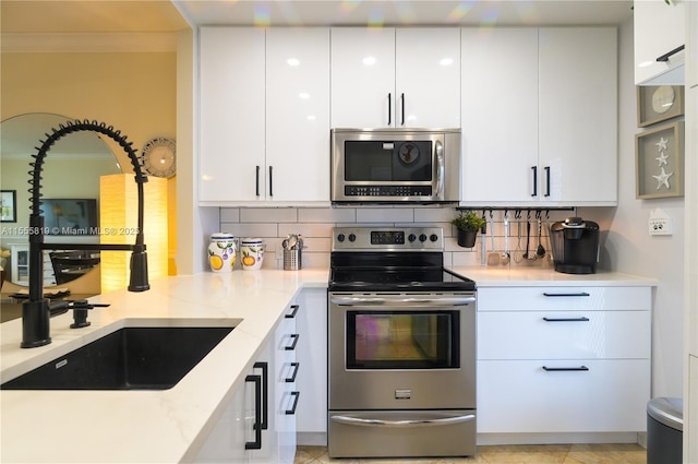 kitchen with tasteful backsplash, appliances with stainless steel finishes, white cabinets, and crown molding